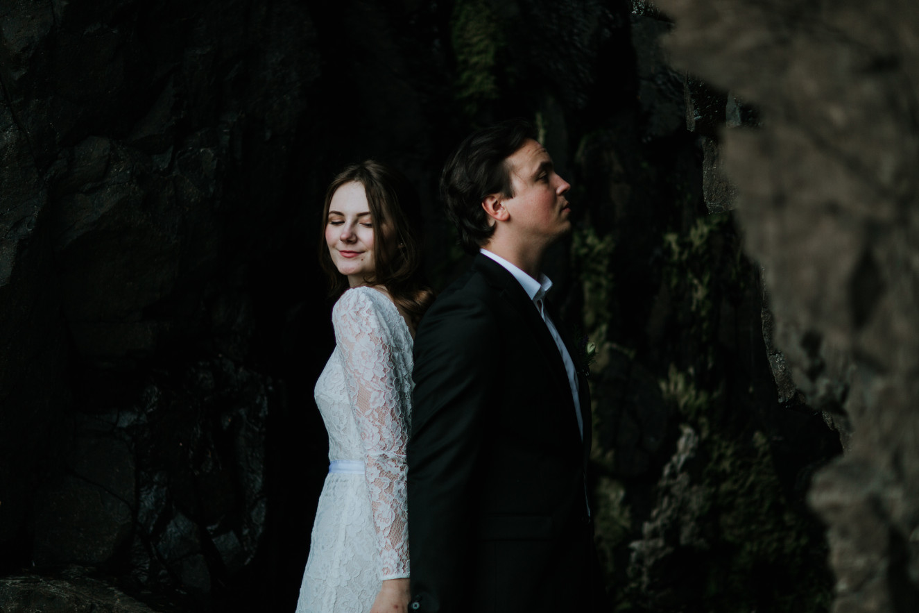 Nicole and Vlad stand back to back near a cliff. Elopement wedding photography at Cannon Beach by Sienna Plus Josh.