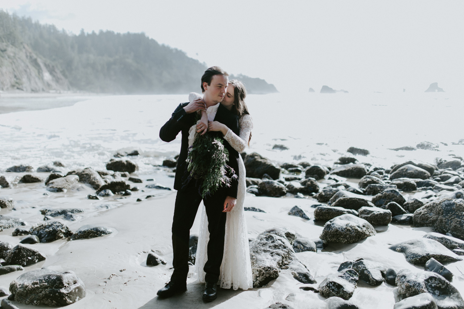 Nicole and Vlad hug near the ocean at Cannon Beach. Elopement wedding photography at Cannon Beach by Sienna Plus Josh.