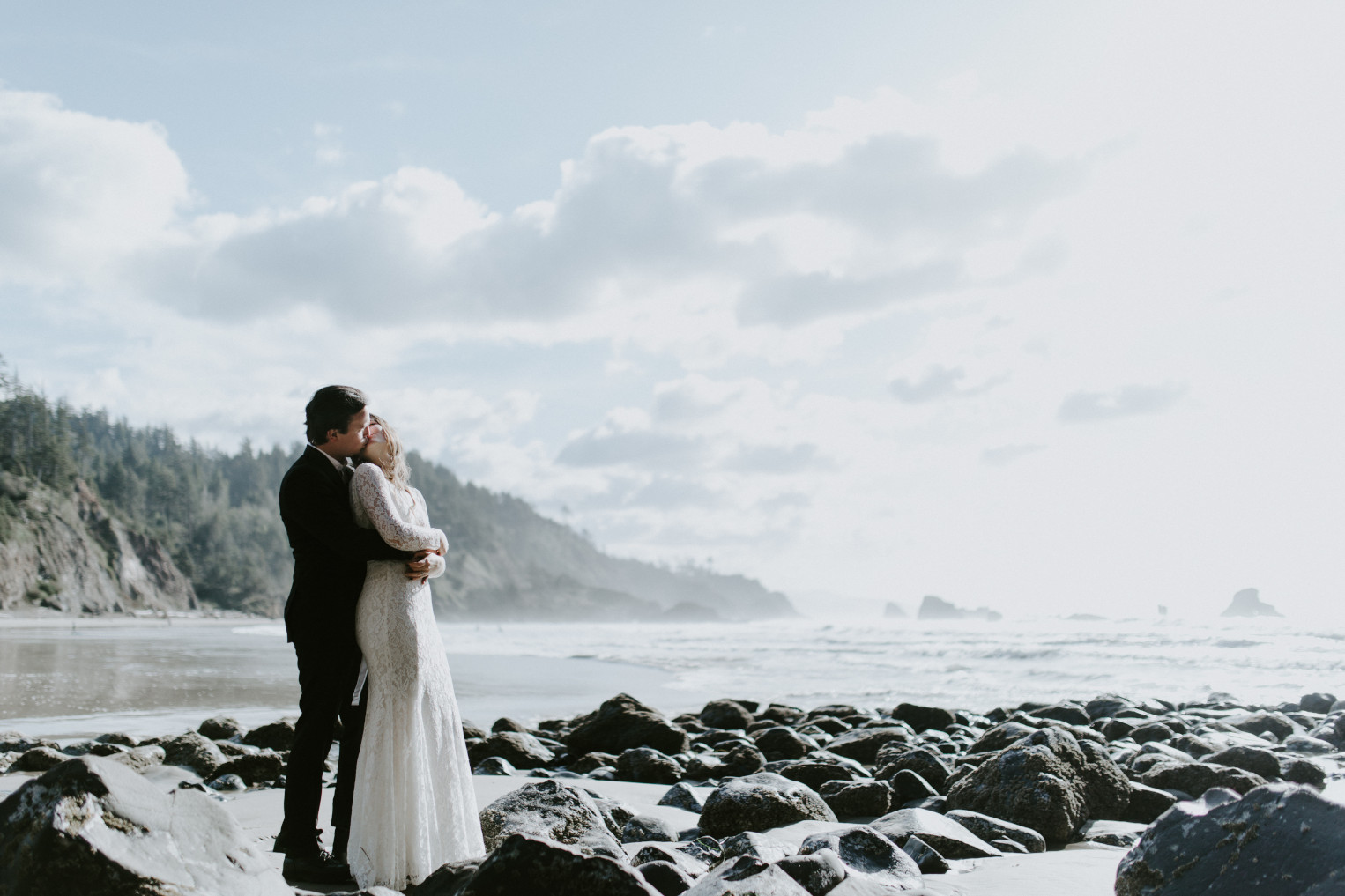 Nicole and Vlad kiss while staning near the ocean. Elopement wedding photography at Cannon Beach by Sienna Plus Josh.