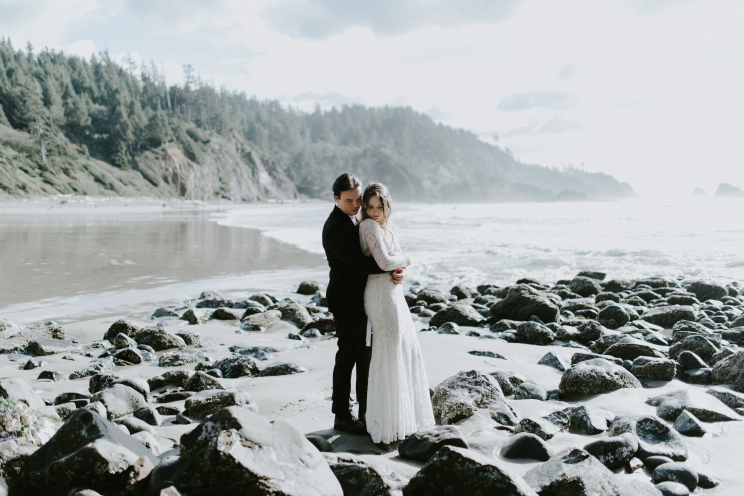 Nicole and Vlad hug while standing on the beach. Elopement wedding photography at Cannon Beach by Sienna Plus Josh.
