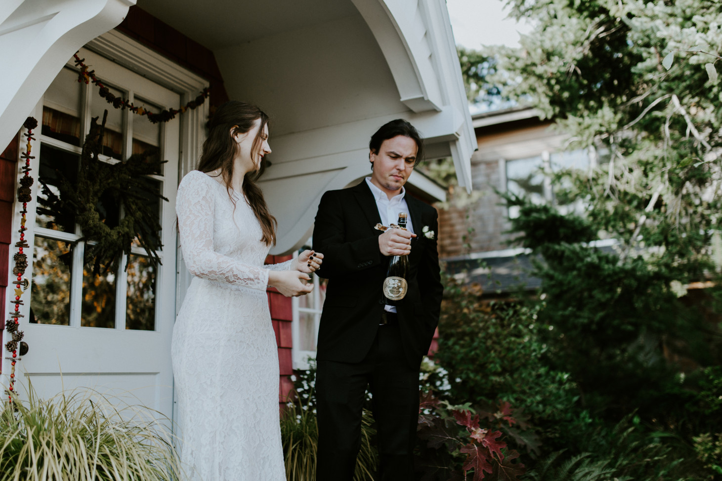 Nicole and Vlad open a bottle of champagne. Elopement wedding photography at Cannon Beach by Sienna Plus Josh.