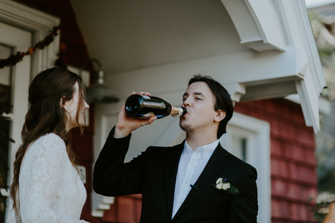 Vlad drinks from a bottle of champagne. Elopement wedding photography at Cannon Beach by Sienna Plus Josh.