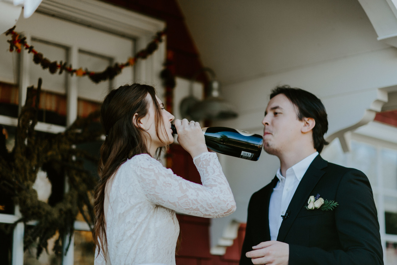 Nicole takes a drink of champagne from the bottle. Elopement wedding photography at Cannon Beach by Sienna Plus Josh.