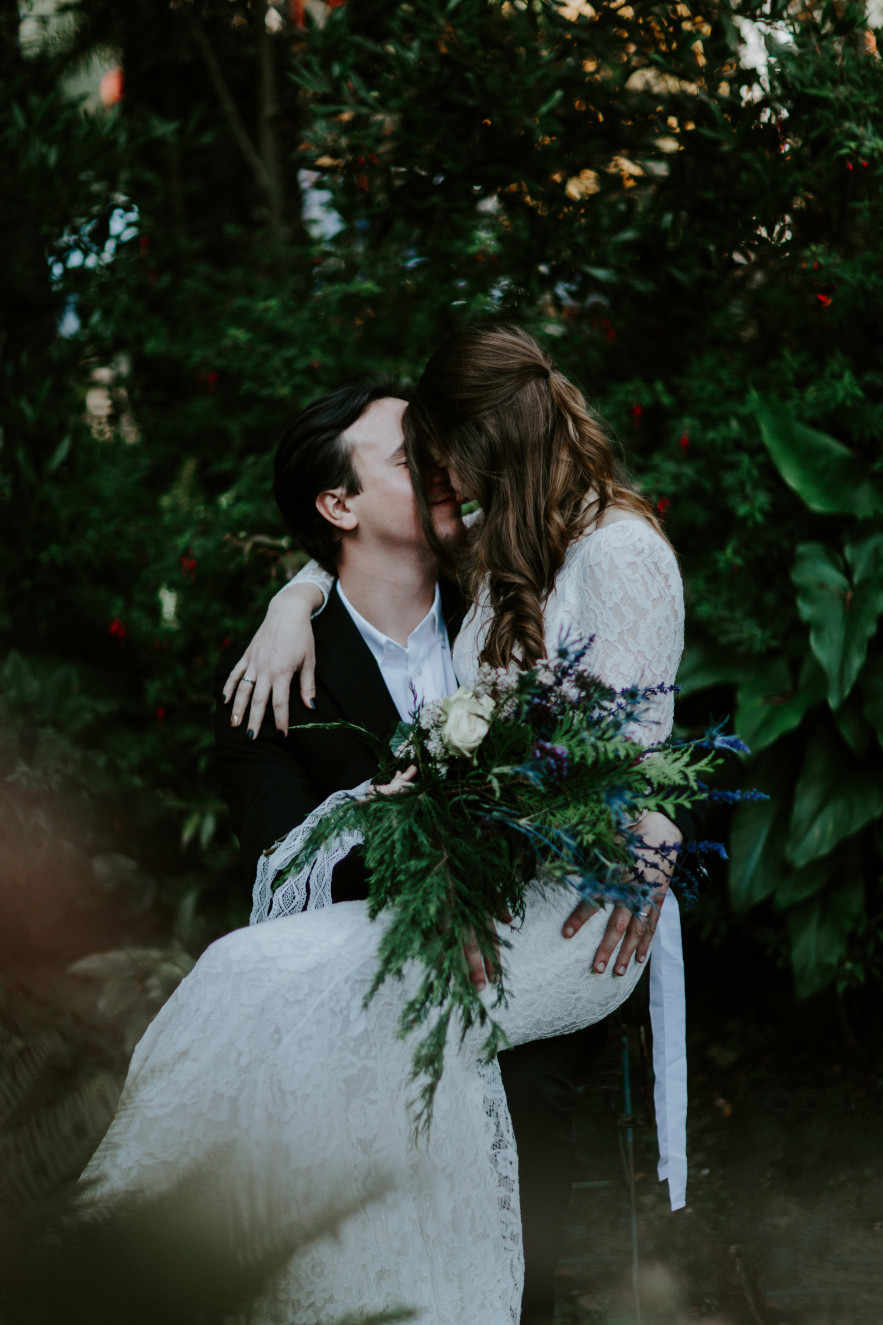 Nicole sits on Vlad's lap in a garden. Elopement wedding photography at Cannon Beach by Sienna Plus Josh.