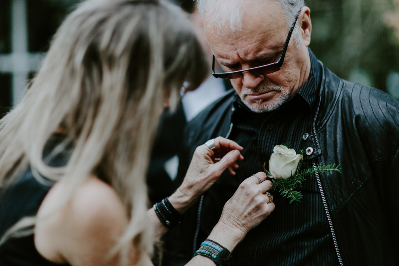Nicole's mom pins flowers to Nicole's dads jacket at Cannon Beach. Elopement wedding photography at Cannon Beach by Sienna Plus Josh.