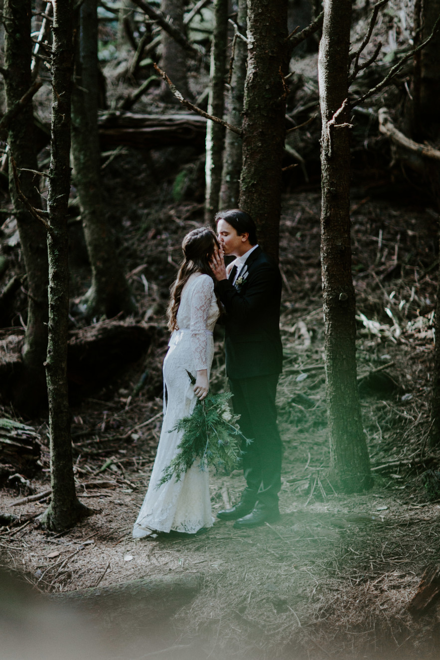 Vlad kisses Nicole's head as they stand in the woods near Cannon Beach. Elopement wedding photography at Cannon Beach by Sienna Plus Josh.
