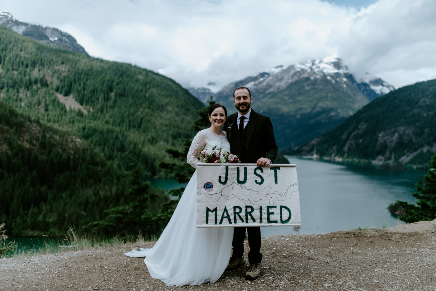Elizabeth and Alex hold up a homemade map of where they eloped at the top of the Diablo Lake Overlook. Elopement photography at North Cascades National Park by Sienna Plus Josh.