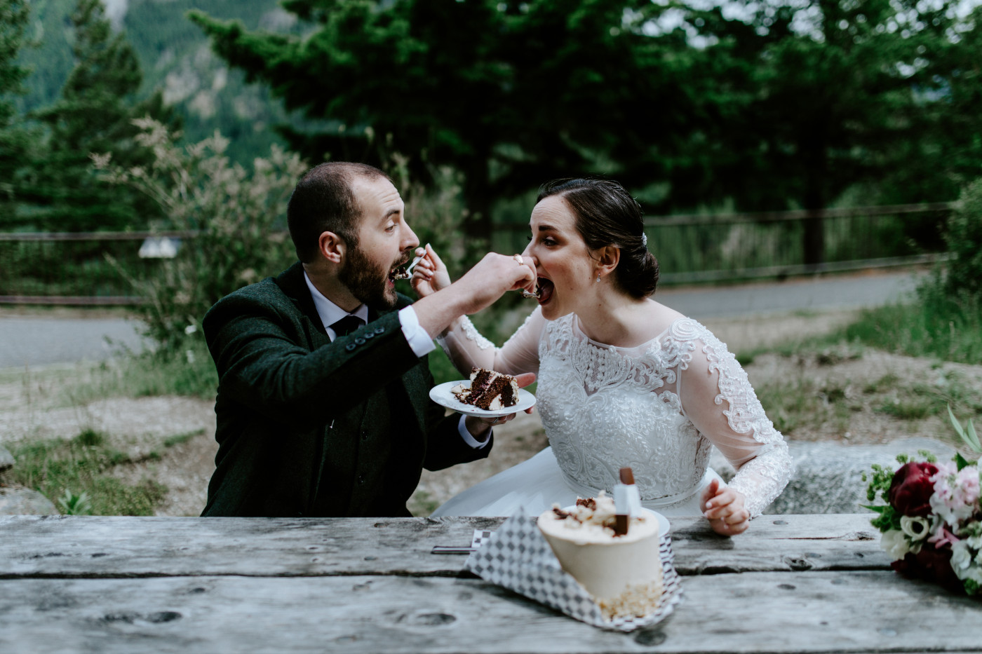 Alex and Elizabeth hold hands while cutting their cake. Elopement photography at North Cascades National Park by Sienna Plus Josh.