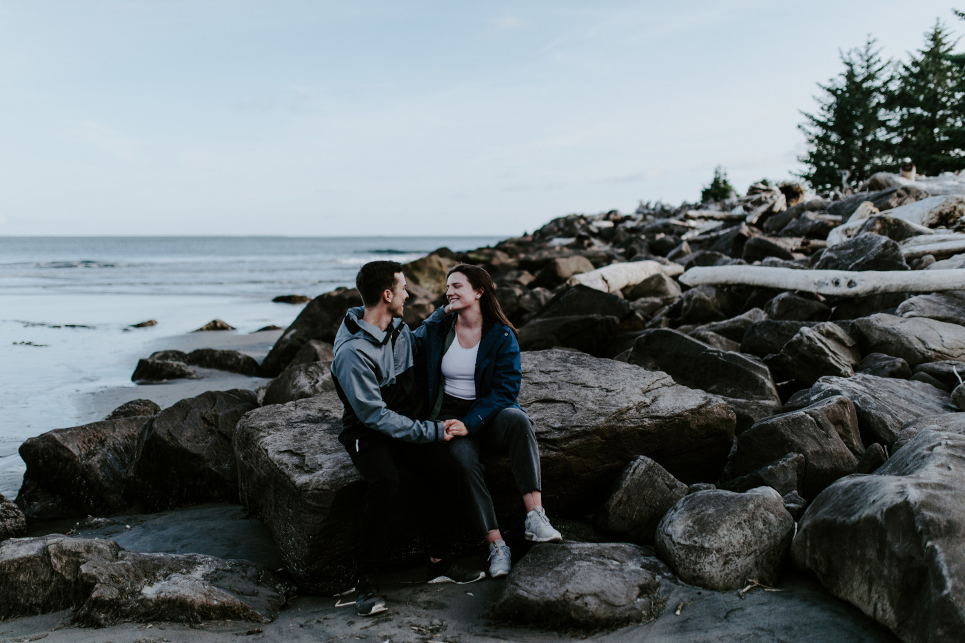 Kyle and Taylor hold hands and sit on the beach. Elopement photography at North Cascades National Park by Sienna Plus Josh.