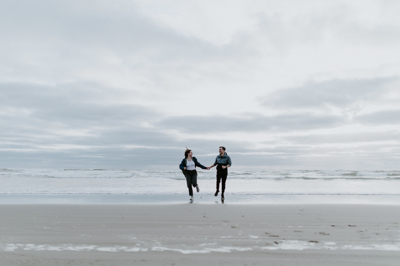 Taylor and Kyle run from the waves. Elopement photography at North Cascades National Park by Sienna Plus Josh.