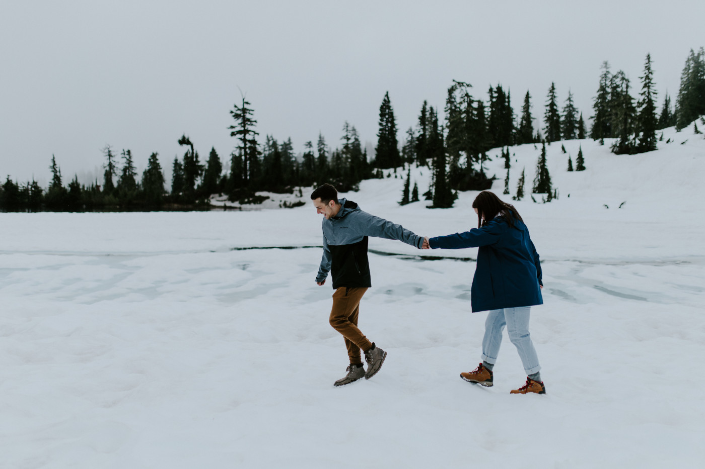 Kyle and Taylor walk next to a frozen lake. Elopement photography at North Cascades National Park by Sienna Plus Josh.