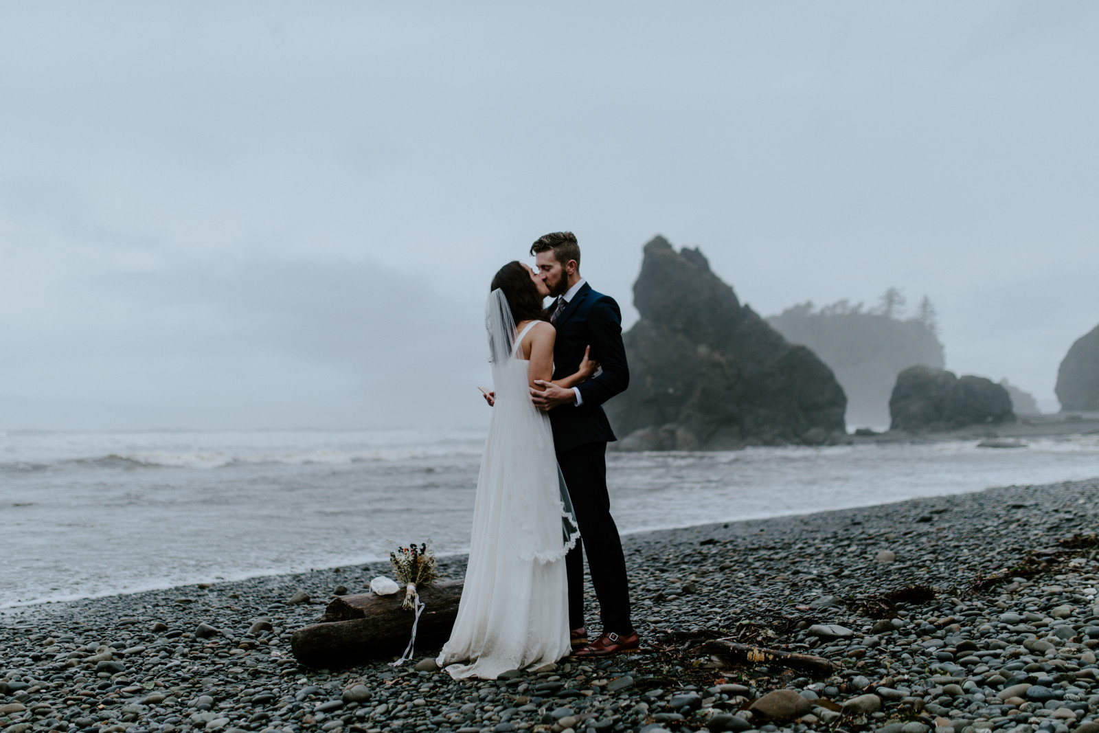 Mollie and Corey kiss on a foggy beach. Elopement photography at Olympic National Park by Sienna Plus Josh.