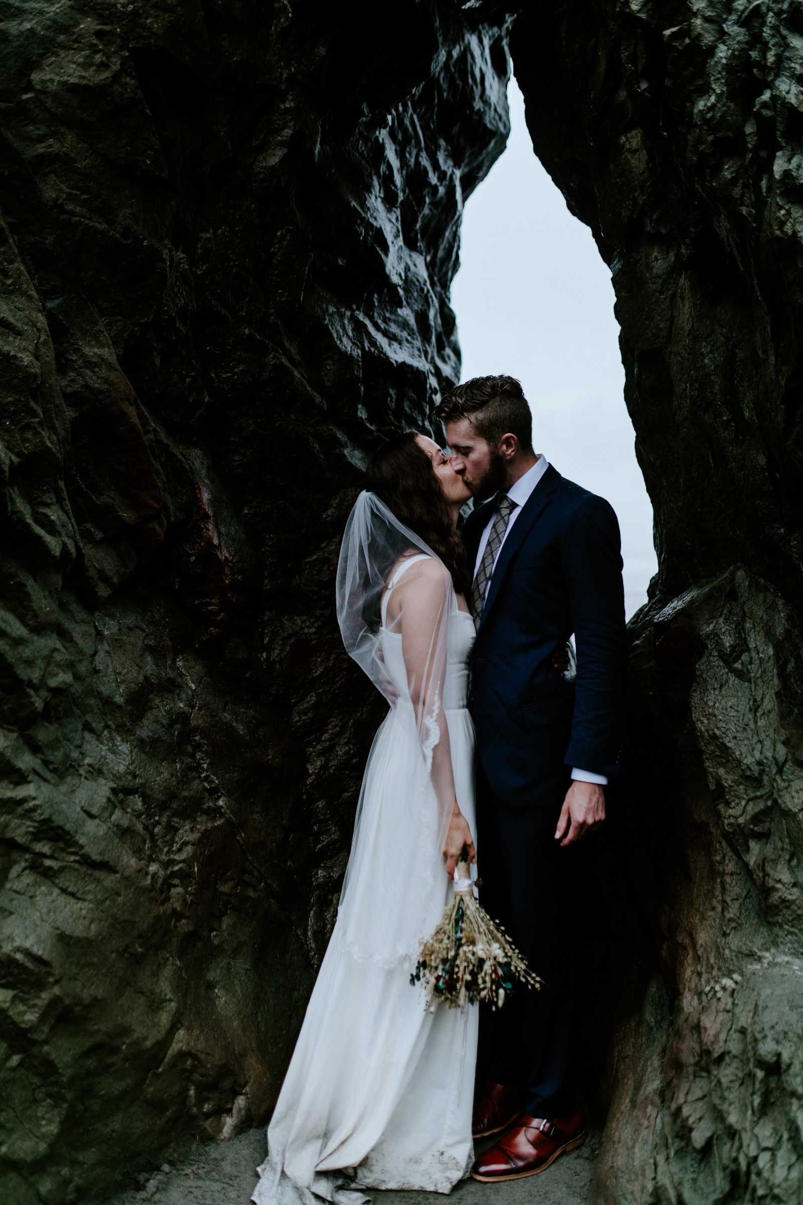 Corey and Mollie kiss in front of a large rock. Elopement photography at Olympic National Park by Sienna Plus Josh.