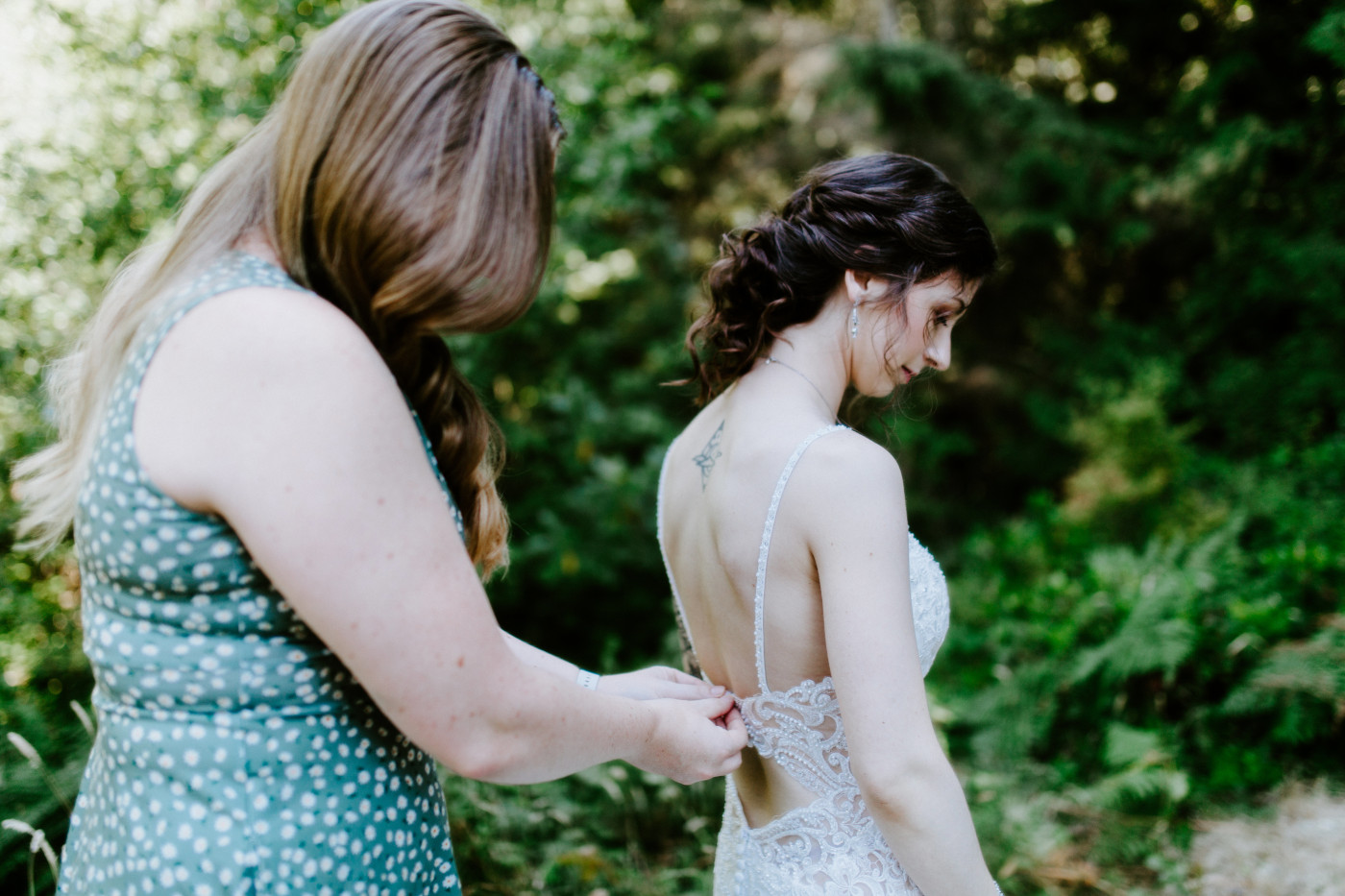 Adrielle gets help zipping up her bridal dress at Olympic National Park, Washington.