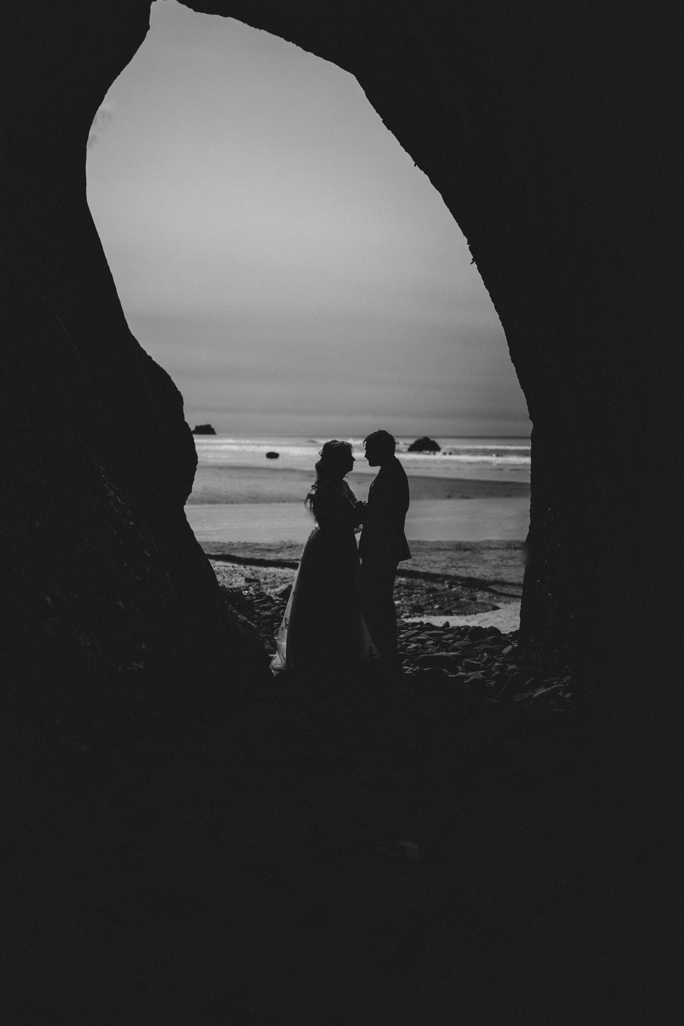 Katie and Ben stand on the beach along the Oregon coast.