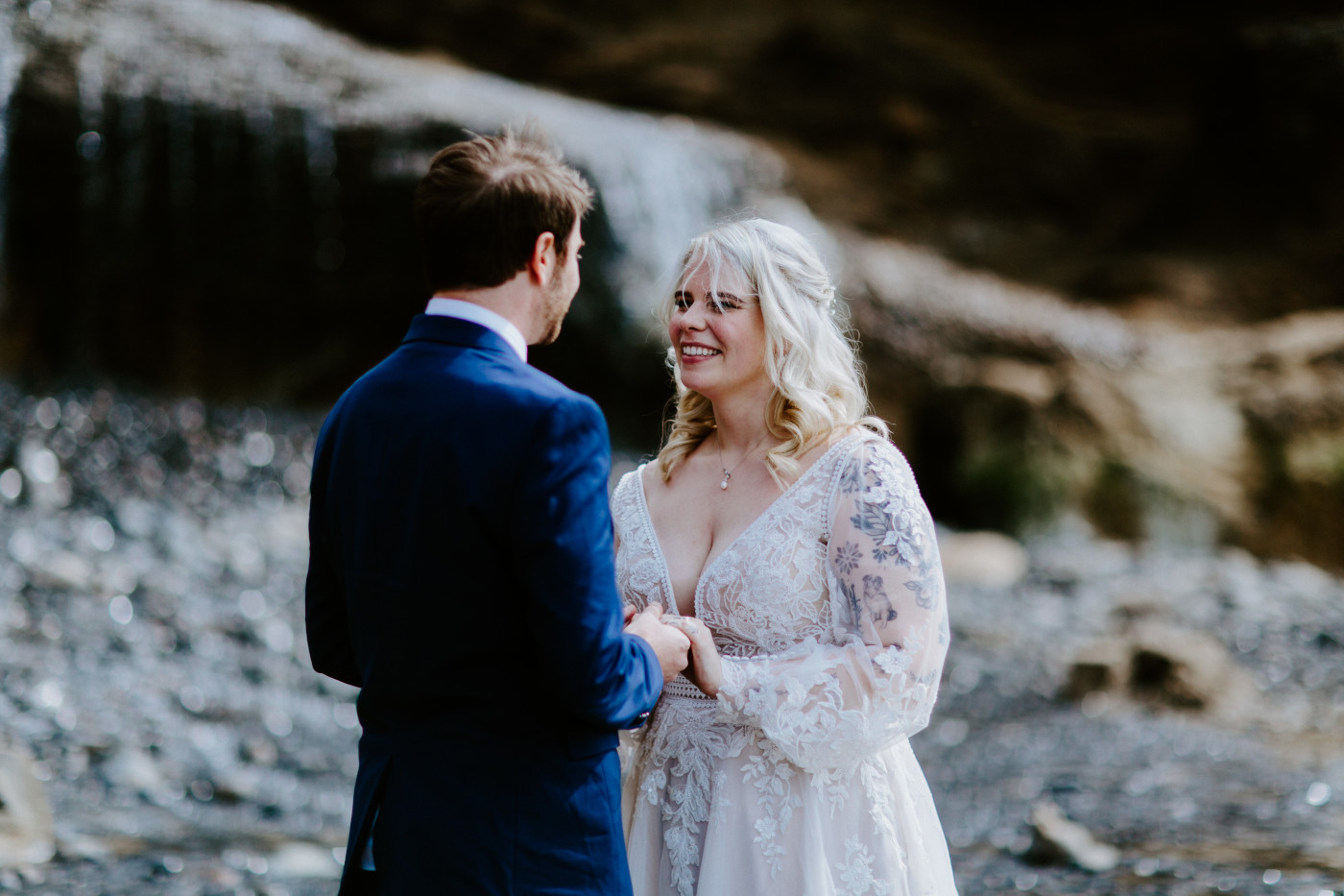 Katie and Ben smile at each other on the beach along the Oregon coast.