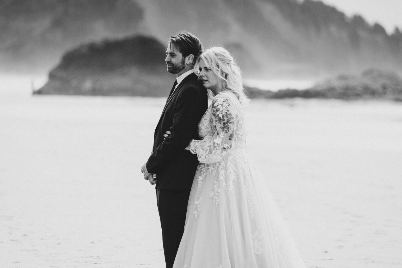 Katie holds onto Ben on the sand on the beach along the Oregon coast.