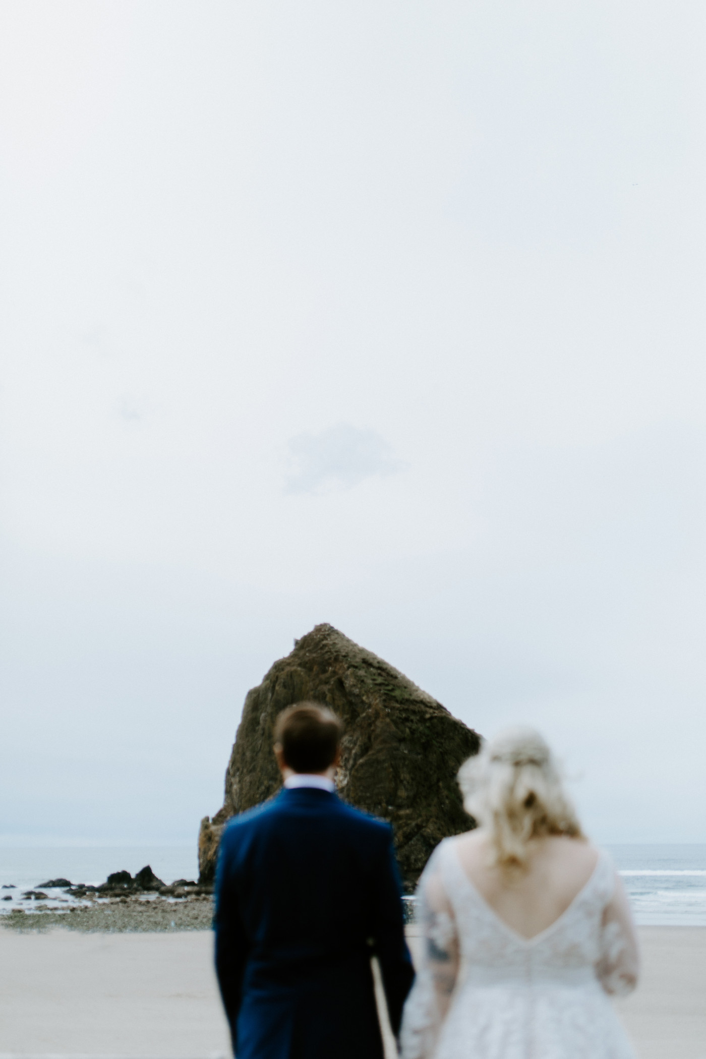 Katie and Ben walk on the sand on the beach along the Oregon coast.