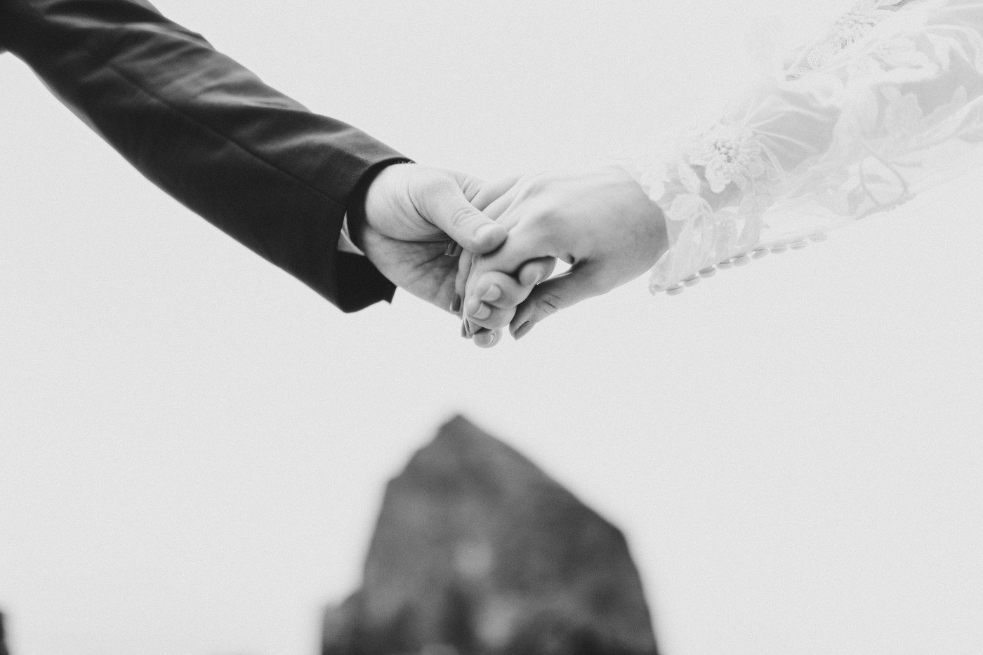 A close up of Katie and Ben holding hands on the sand on the beach along the Oregon coast.