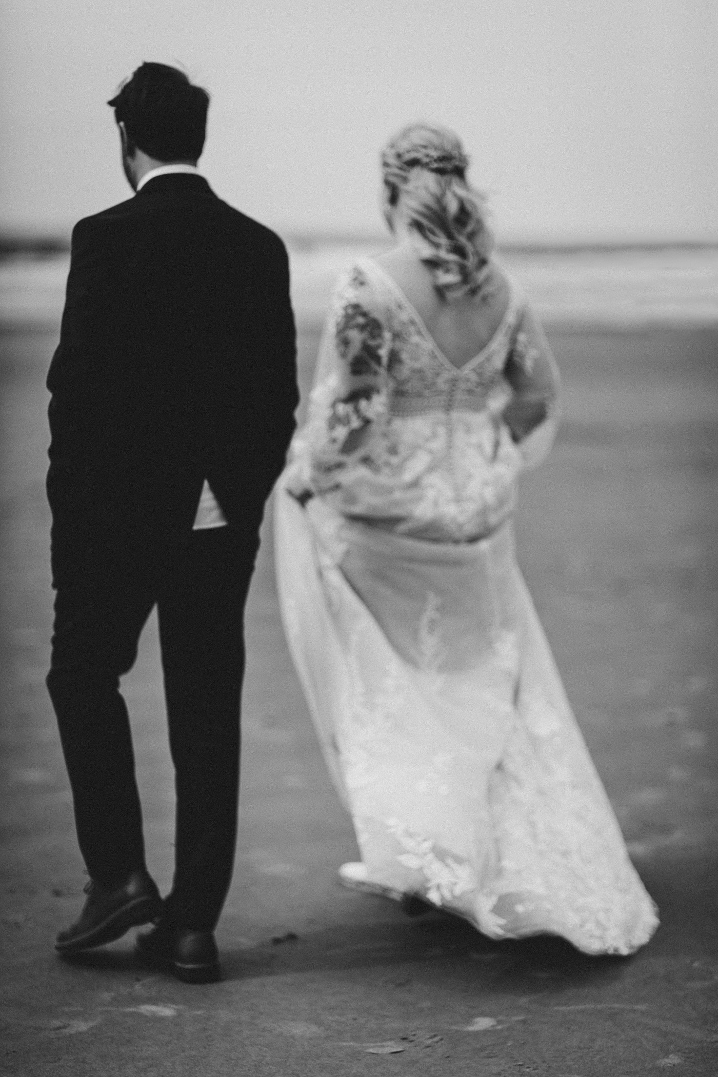 Katie and Ben walking away on the sand on the Oregon coast.