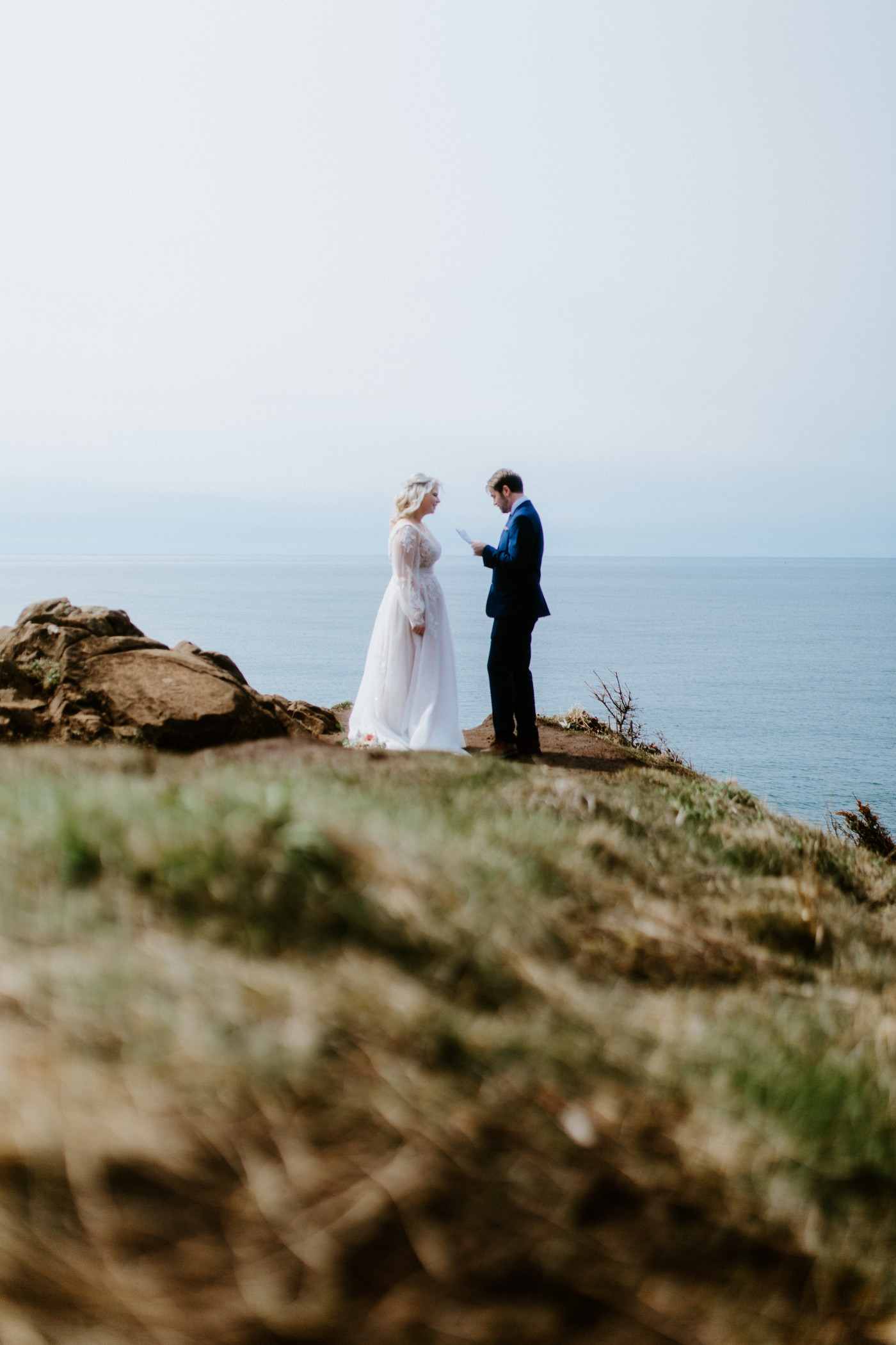 Katie listens to  Ben's vows at the Oregon coast during their elopement ceremony.