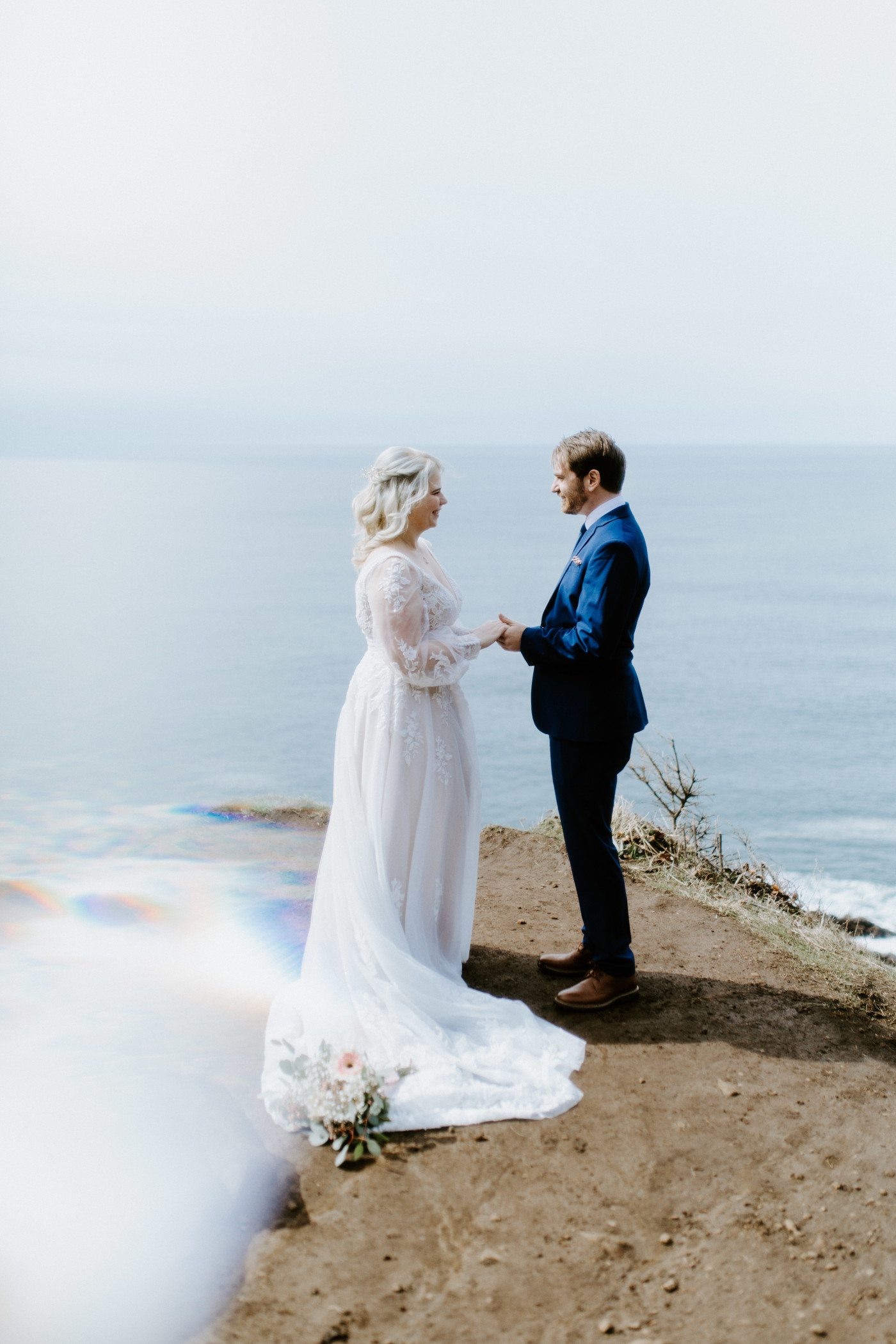 Ben and Katie stand hand in hand at the Oregon coast during their elopement ceremony.