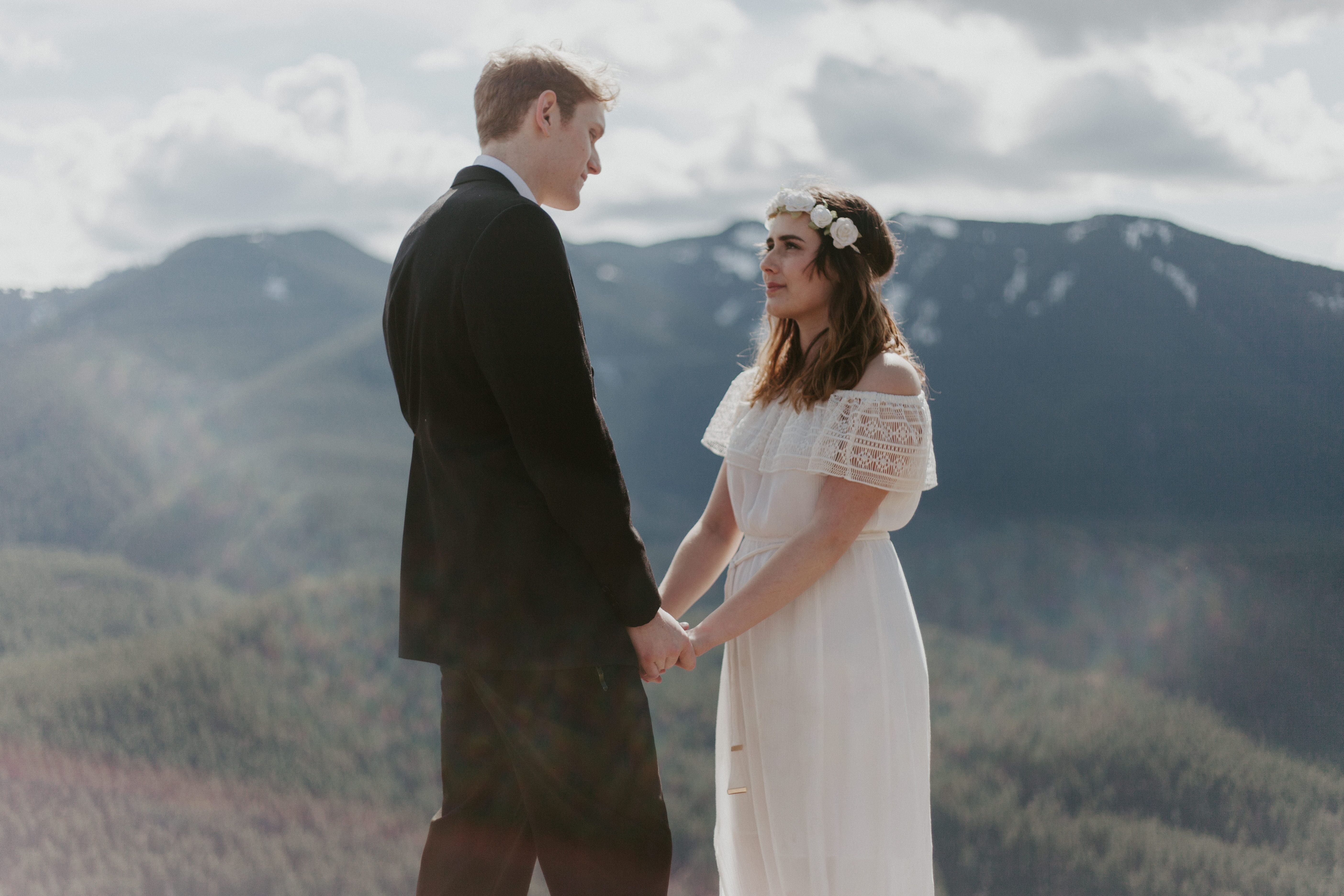 Michael and Winnifred hold hands with a view of Washington state in the background. Elopement adventure shoot at Rattlesnake Ledge, Washington.