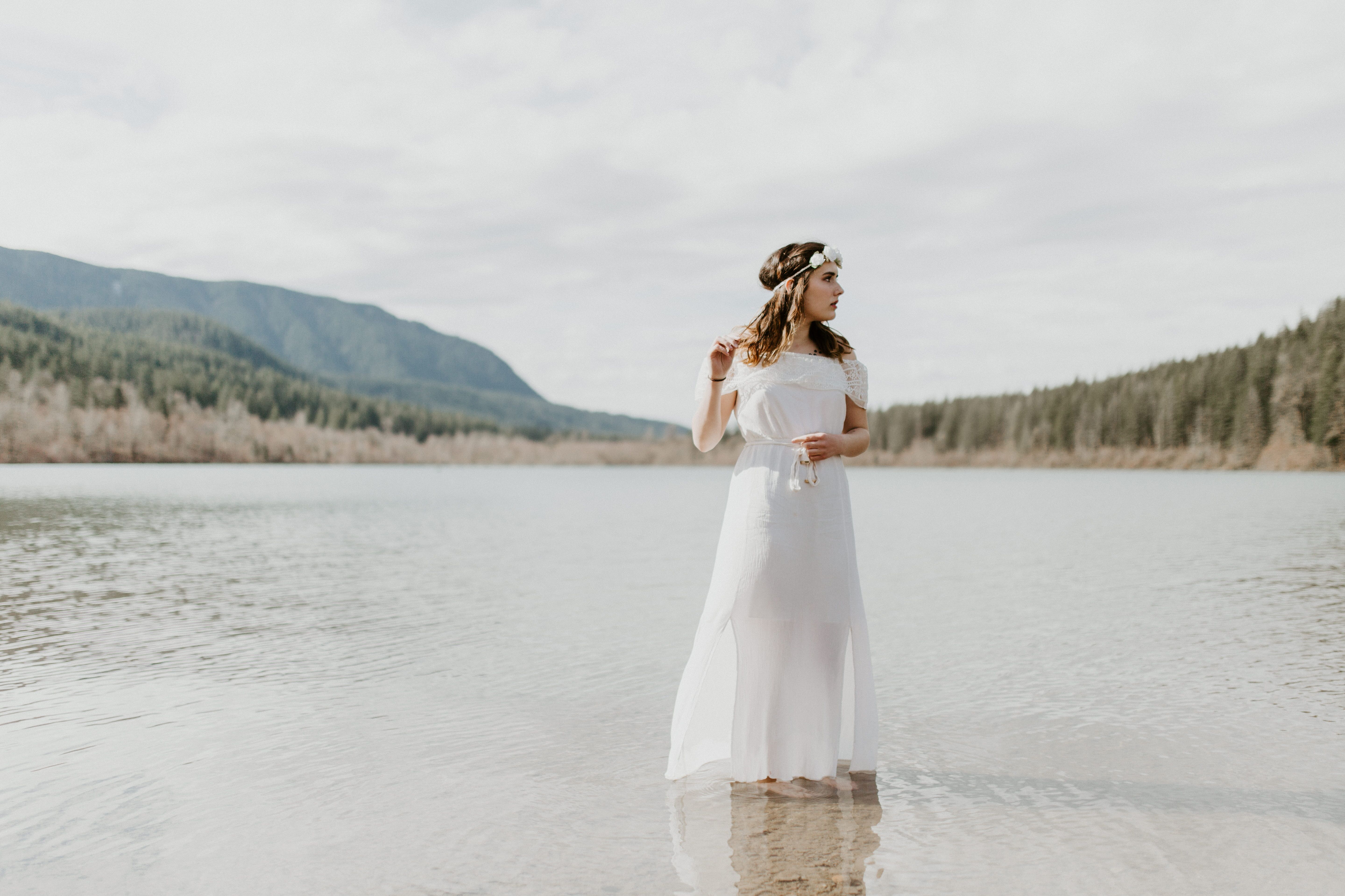 Winnifred stands in Rattlesnake Lake with the view of the trees behind her. Elopement adventure shoot at Rattlesnake Lake, Washington.