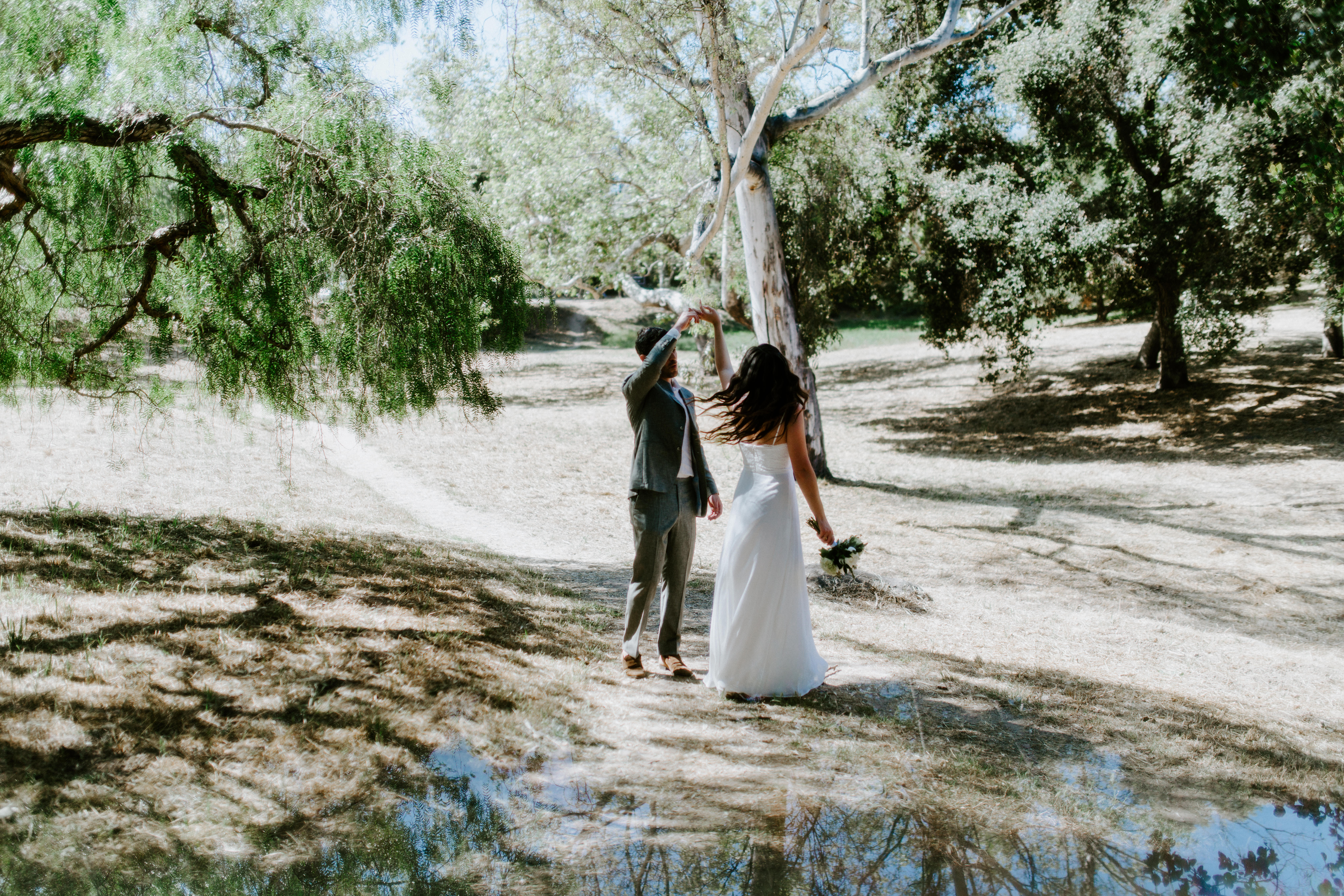 A newlywed couple dances, surrounded by trees in Santa Barbara, California.