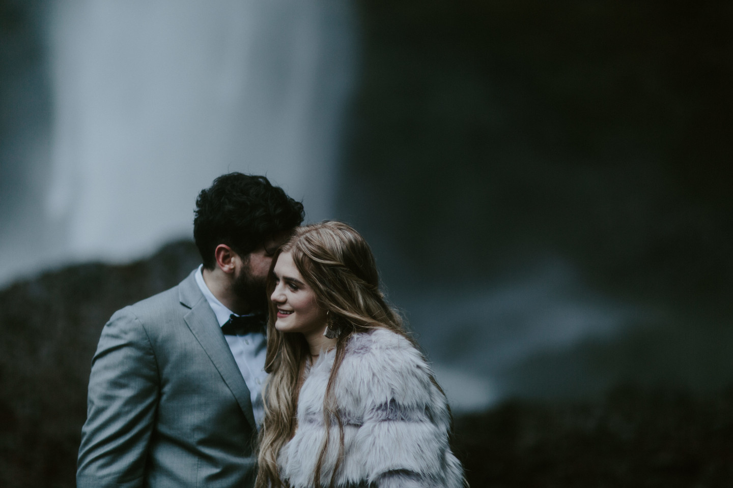 Boris whispers to Tyanna  in front of Latourell Falls, OR. Adventure elopement in the Columbia River Gorge by Sienna Plus Josh.