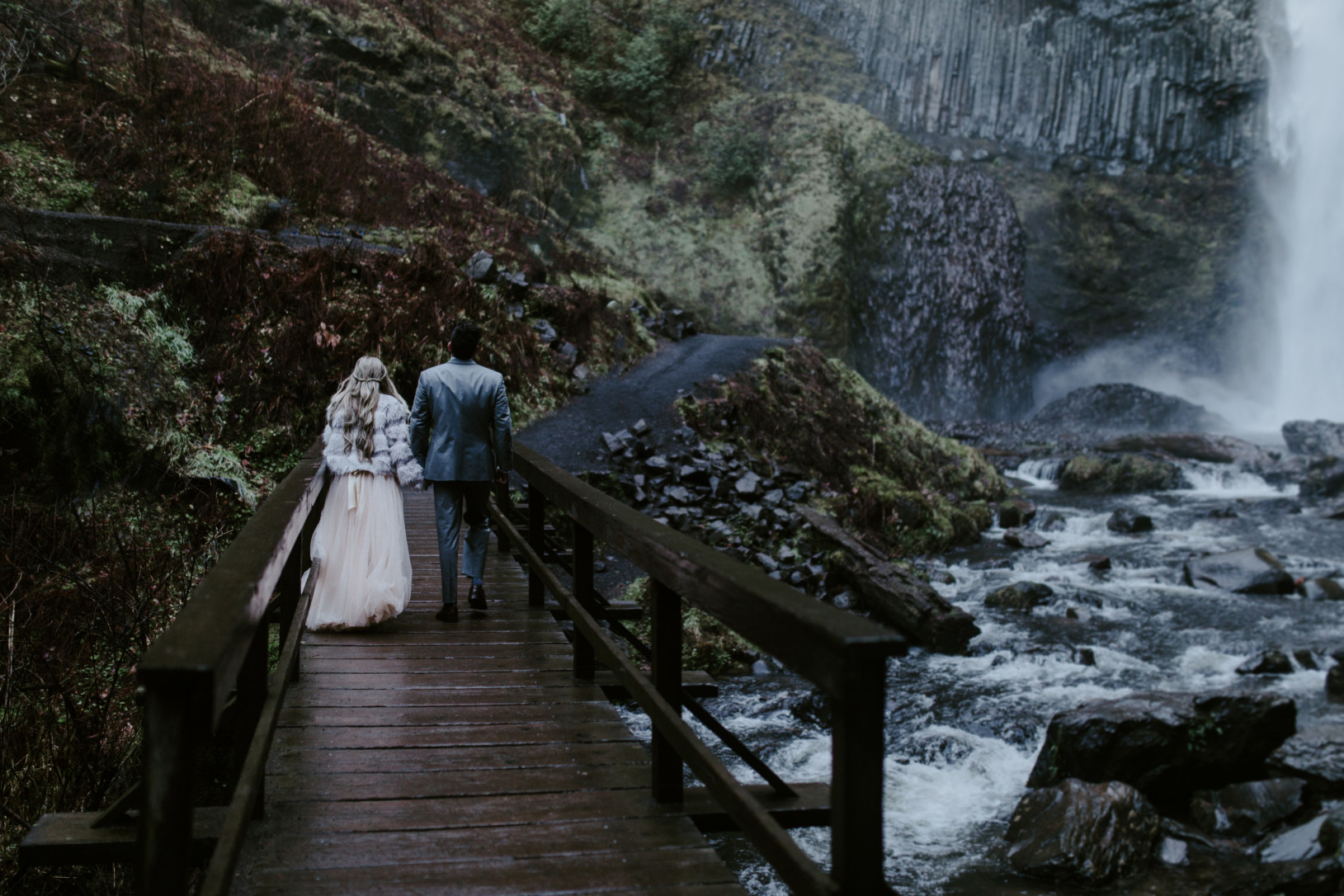 Boris holds Tyanna's hand as the cross the bridge at Latourell Falls, OR. Adventure elopement in the Columbia River Gorge by Sienna Plus Josh.
