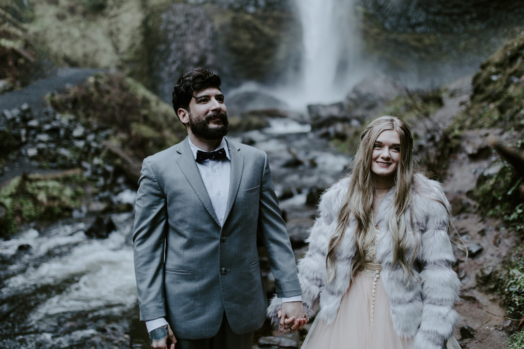 Boris and Tyanna hold hands along a stream at Latourell Falls. Adventure elopement in the Columbia River Gorge by Sienna Plus Josh.