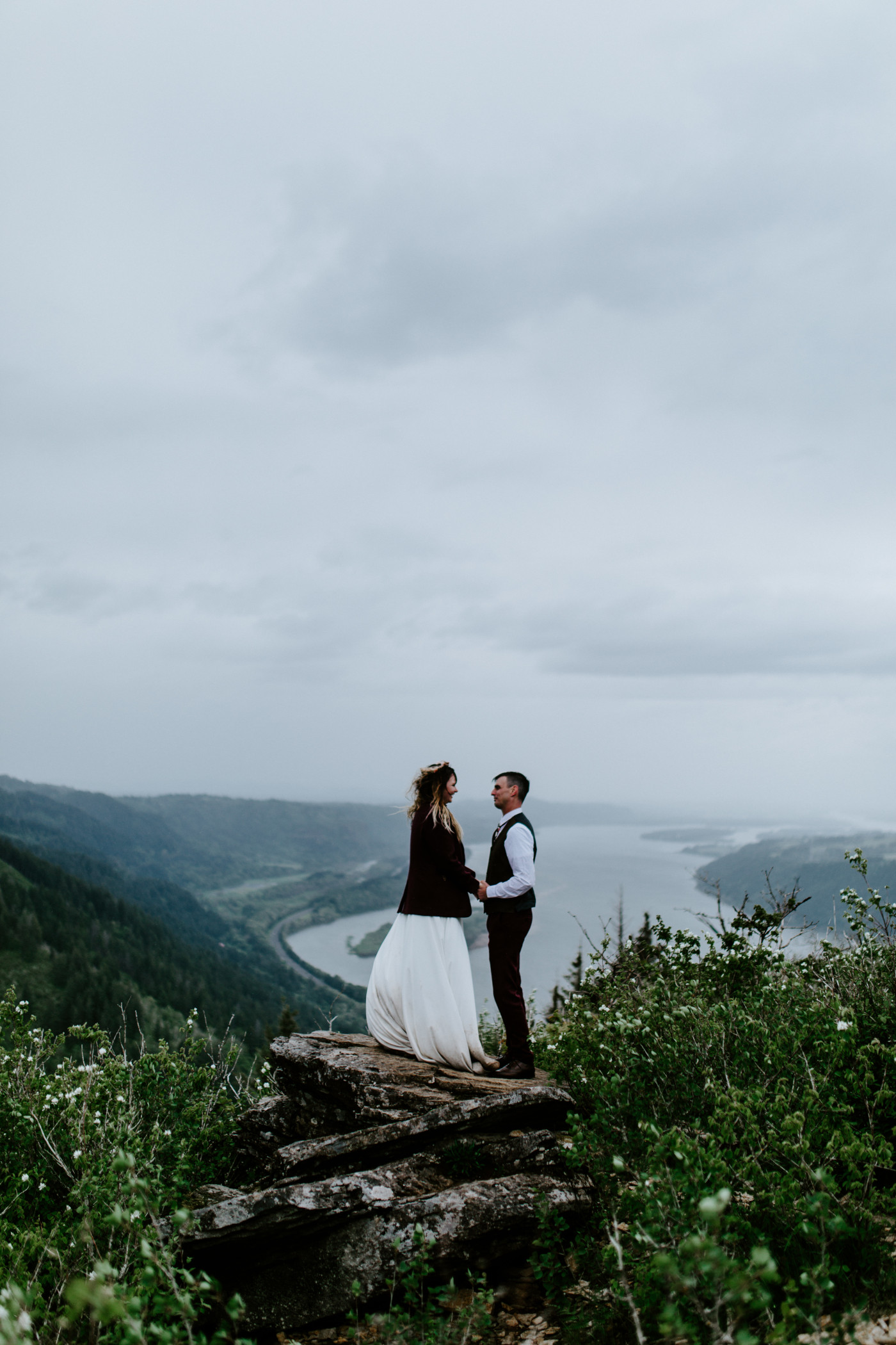 Jordan and Andrew stand holding hands with the Columbia River in the background.